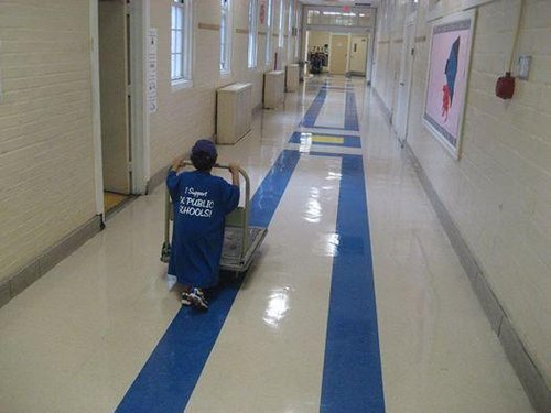 Robert's son pushing a cart down a hallway in oversized DCPS t-shirt